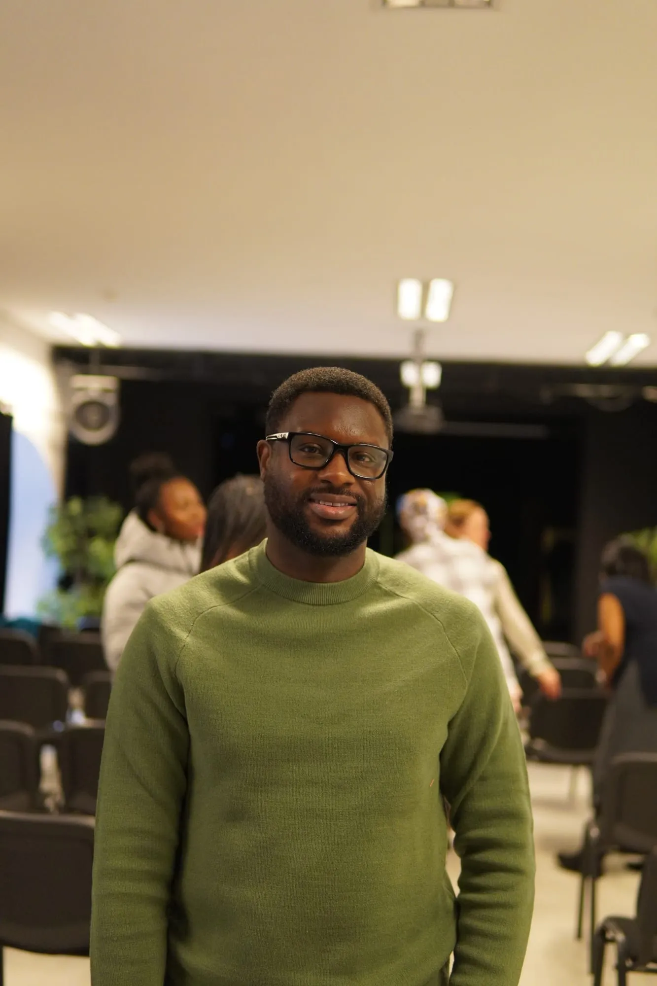 A man in glasses and a green jumper smiling