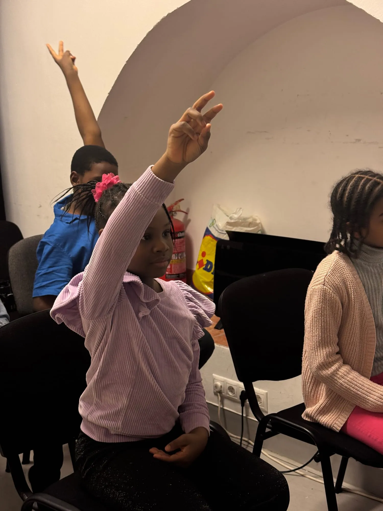 A girl in Children's Church raising her hand high to answer